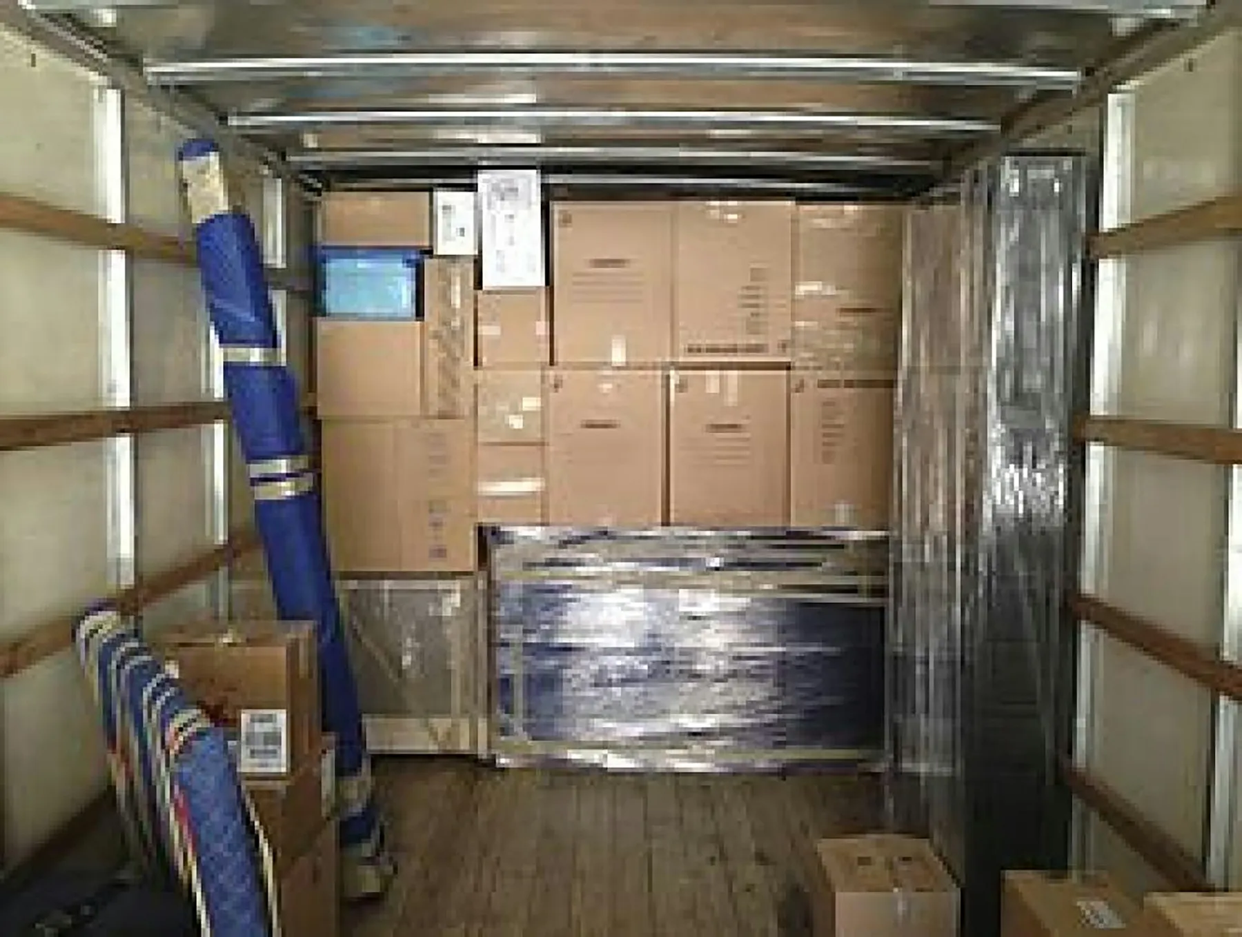 Inside a moving truck packed with boxes, blankets and shrink-wrapped furniture