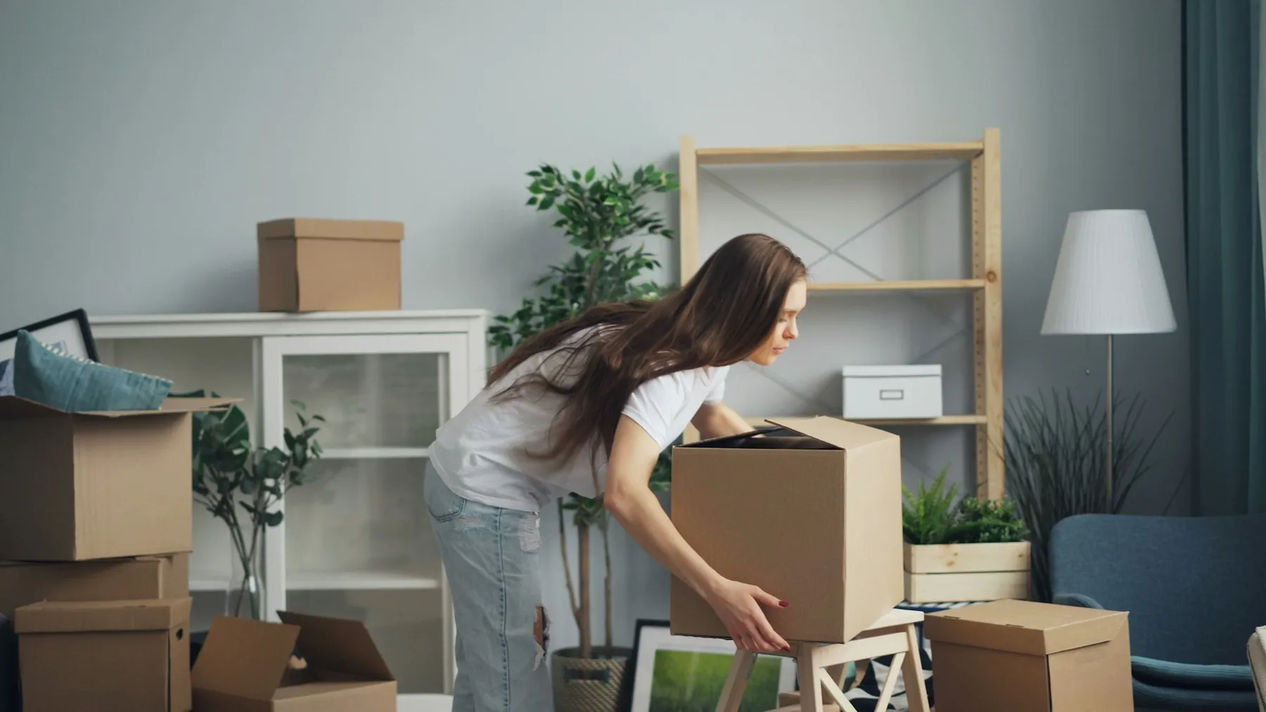 Woman lifting a packed cardboard box in a living room